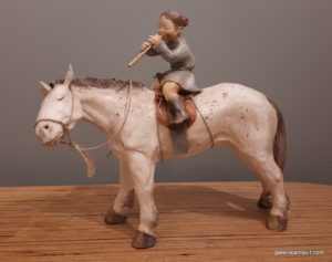 sculpture en terre cuite de Sandra Courlivant,enfant jouant de la flûte sur un cheval - profil